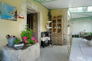 A room with a dining table, chairs, a cabinet with dishes, a clock, and a painting on the wall. - Hermione Guest Room with Shared Terrace, Communal Garden and Wi-Fi (Pont-l'Abbé-d'Arnoult)