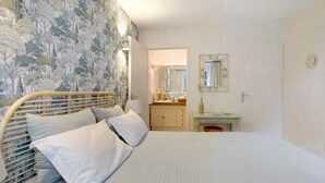 Une chambre à coucher avec un lit, une table de chevet, une commode et un miroir.