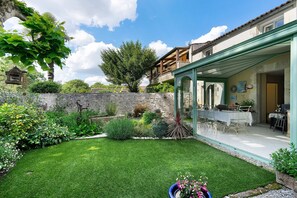 A well-maintained garden with a patio, stone wall, and a dining area with outdoor furniture.