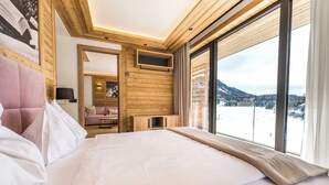 Une chambre d’hôtel moderne avec un grand lit, des murs en bois, une télévision et une vue sur un paysage enneigé.