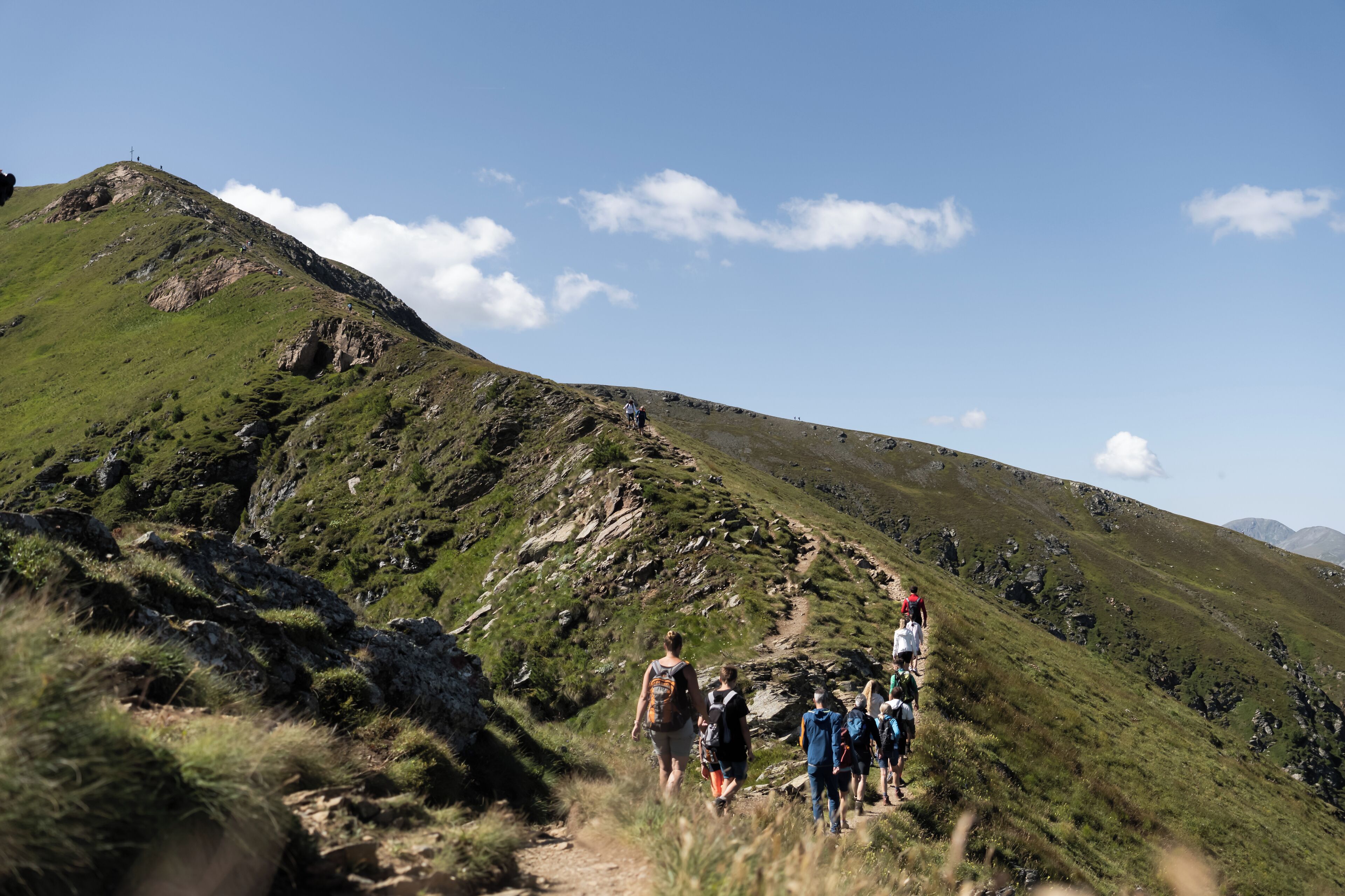 Eine Gruppe von Wanderern auf einem grasbewachsenen Bergpfad.