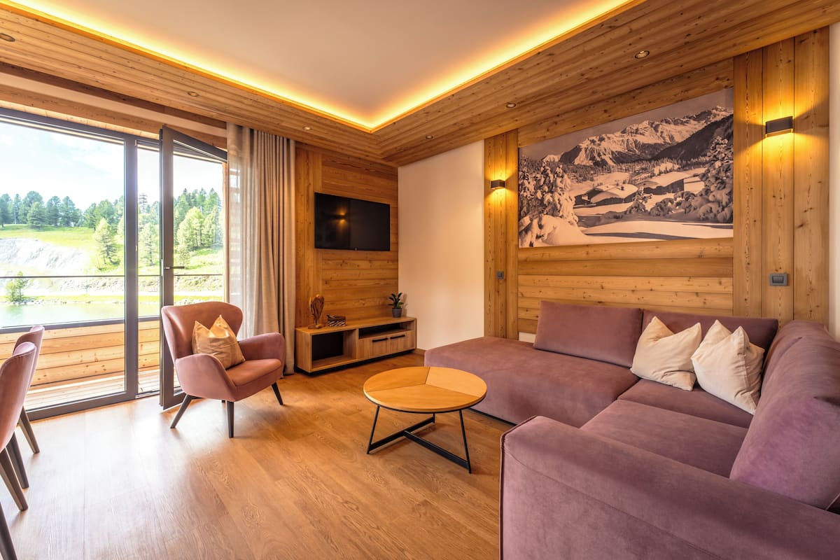 A modern living room with a wooden ceiling, a large window, a sofa, a chair, and a coffee table.
