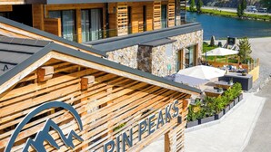 Un hôtel à plusieurs étages, doté d’une façade en bois, de places assises en plein air et offrant une vue sur un lac.