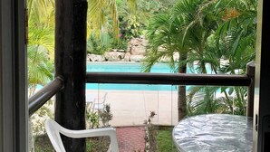 Un balcon donnant sur une piscine, entourée de palmiers et de verdure.