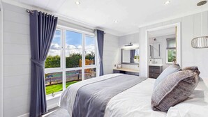 A bedroom with a large bed, a bathroom with a mirror, and a view of the outdoors. - Host & Stay | Marble Lodge (Beverley)