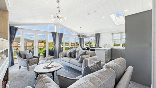 A spacious living area with a sofa, armchairs, a coffee table, and a view of the outdoors through large windows. - Host & Stay | Marble Lodge (Beverley)