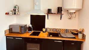 Eine kleine Küche mit Mikrowelle, Kaffeemaschine und Espressokocher.