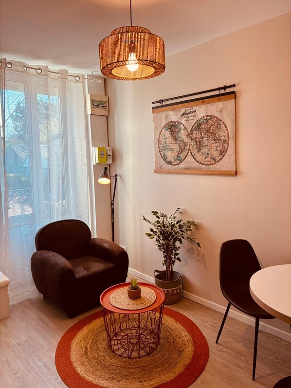 Ein Wohnzimmer mit einem braunen Ledersessel, einem runden Couchtisch, einer Topfpflanze, einer Weltkugel als Kunstwerk und einer Hängelampe.