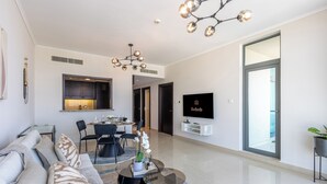 Una sala de estar moderna con un sofá, una mesa de comedor, sillas, una mesa de centro, un televisor y un ventanal grande.