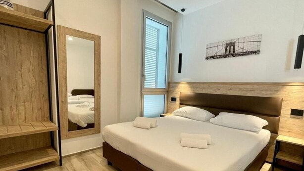Ένα υπνοδωμάτιο με ένα κρεβάτι, μια ντουλάπα, έναν καθρέφτη και ένα παράθυρο.
