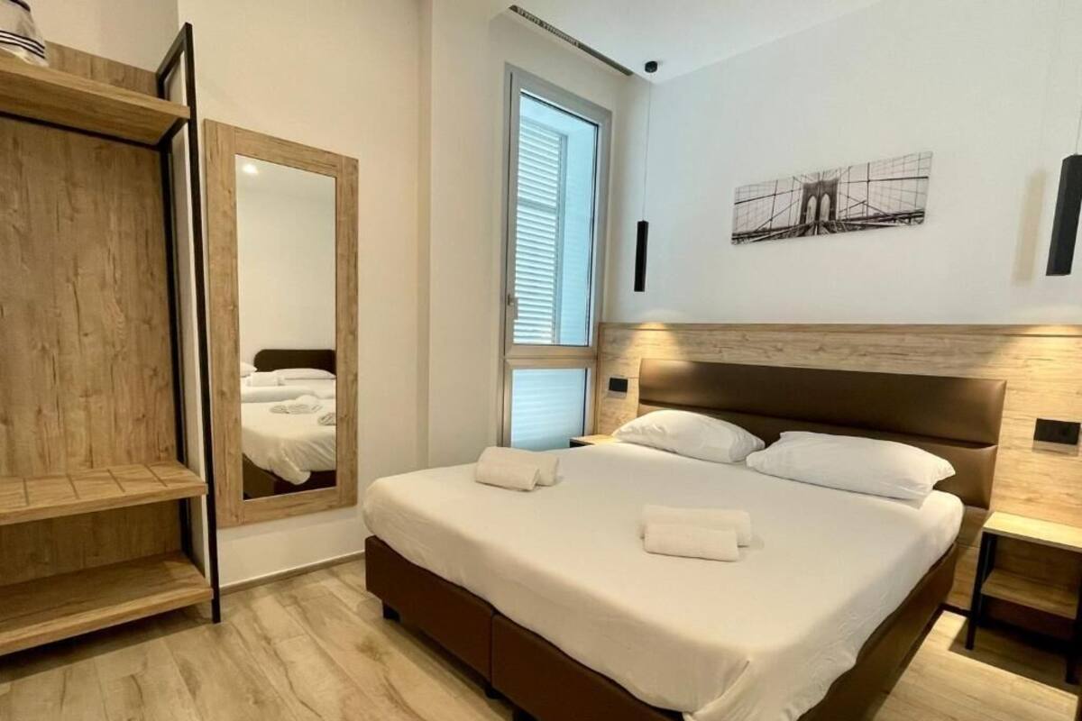 Un dormitorio con cama, armario, espejo y ventana.