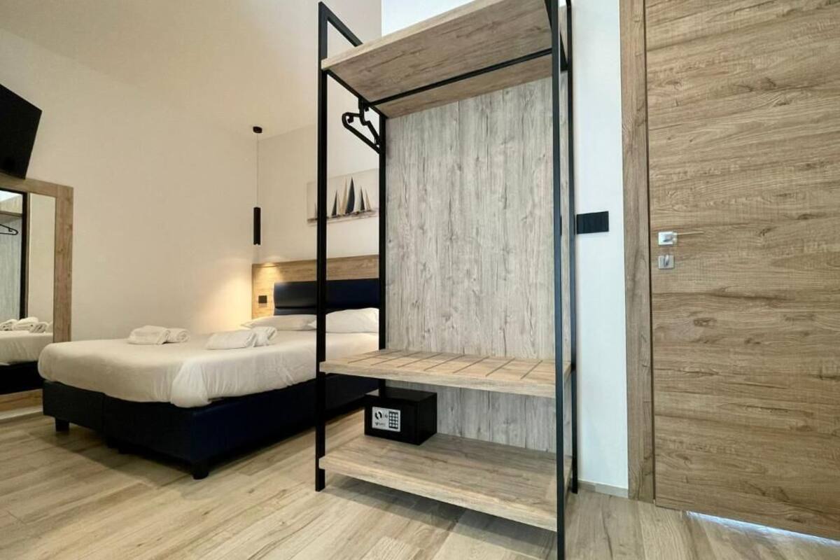 Una habitación de hotel moderna con una cama litera, un armario de madera y una pequeña estantería.