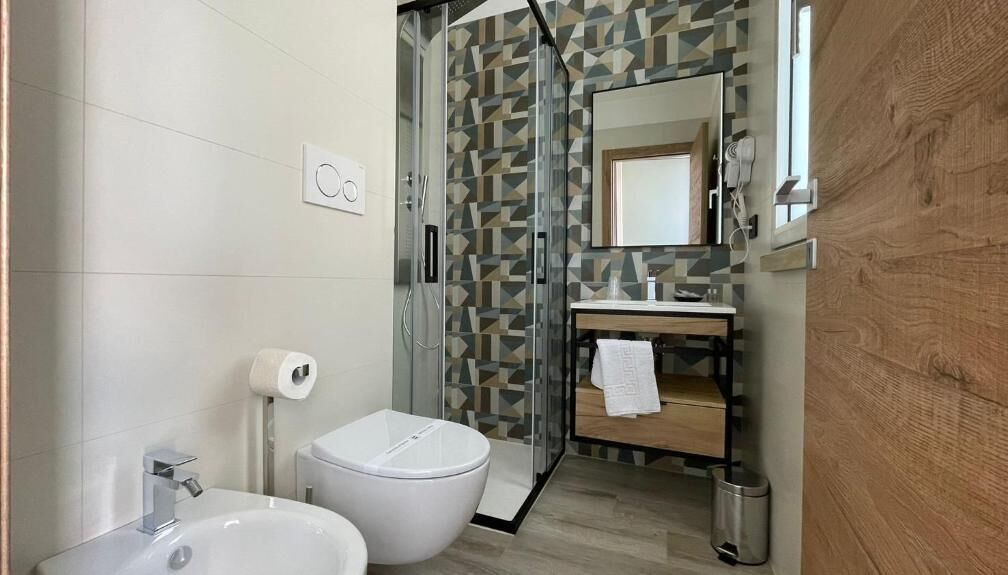 A modern bathroom with a glass shower enclosure, a white sink, and a toilet.