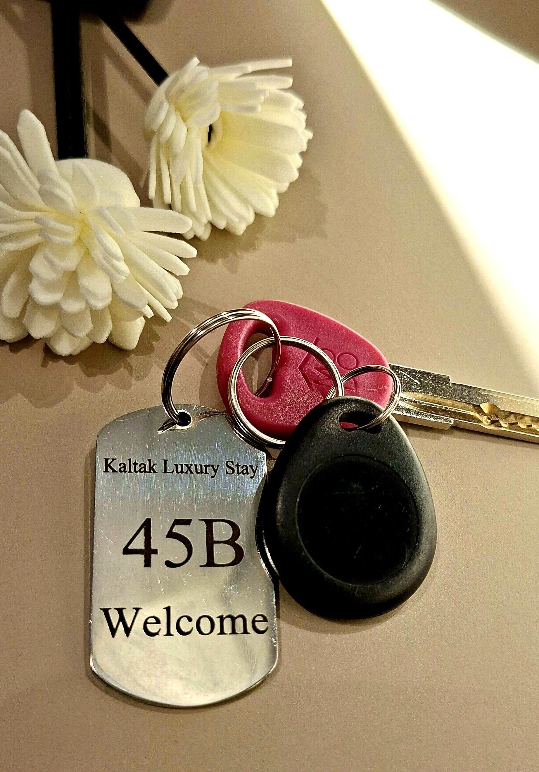 Una llave con una etiqueta metálica que dice 'Kaltak Luxury Stay 45B Welcome'.