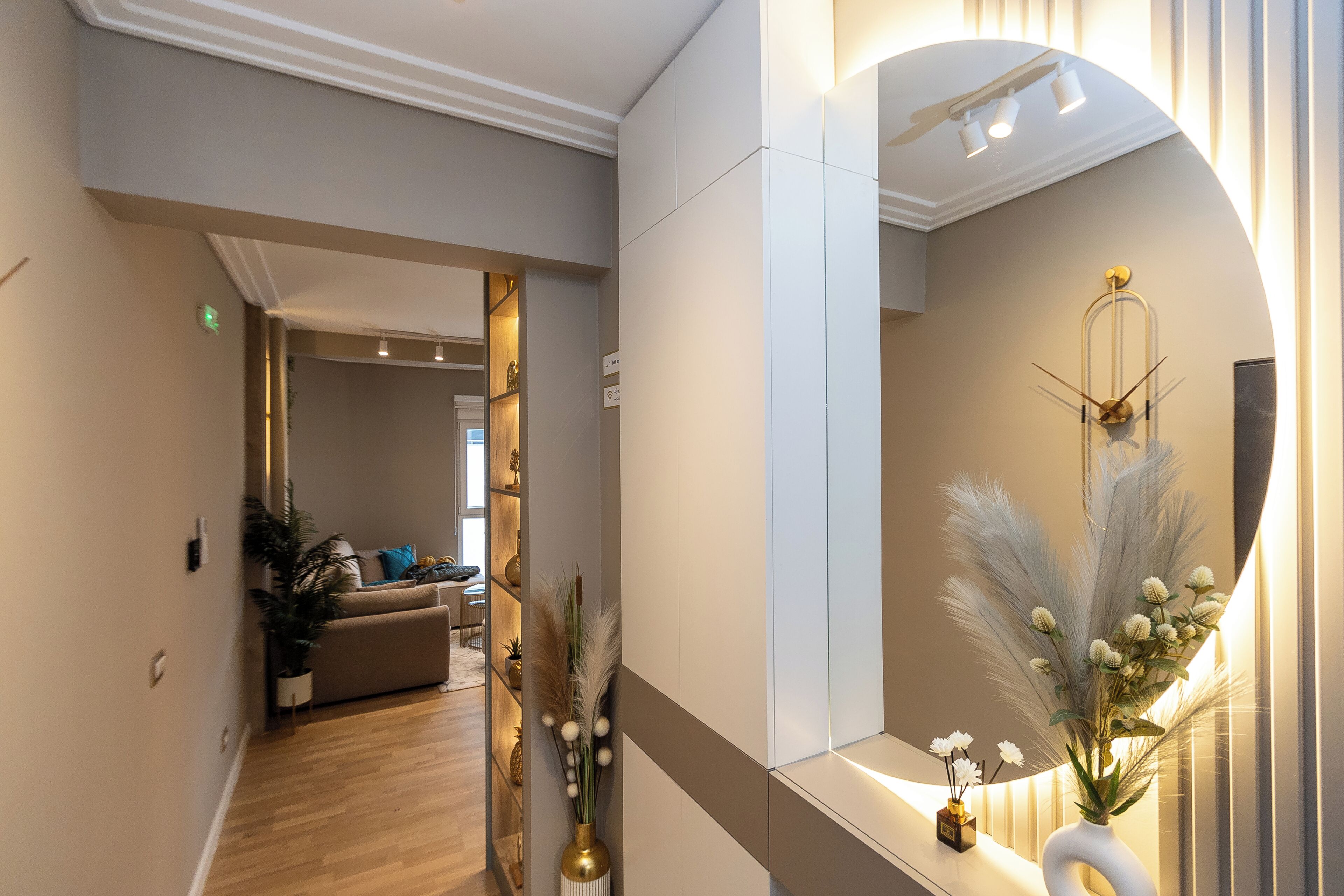 A hallway with a mirror, a plant, and a decorative wall piece.