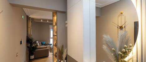 A hallway with a mirror, a plant, and a decorative wall piece.