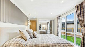 Une chambre avec un grand lit, une armoire, un miroir et une vue sur l’extérieur.