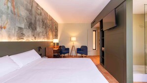 A hotel room with a large bed, a desk with two chairs, a wall-mounted TV, and a large abstract painting. - El Vilar de la Duquessa (Cardona)