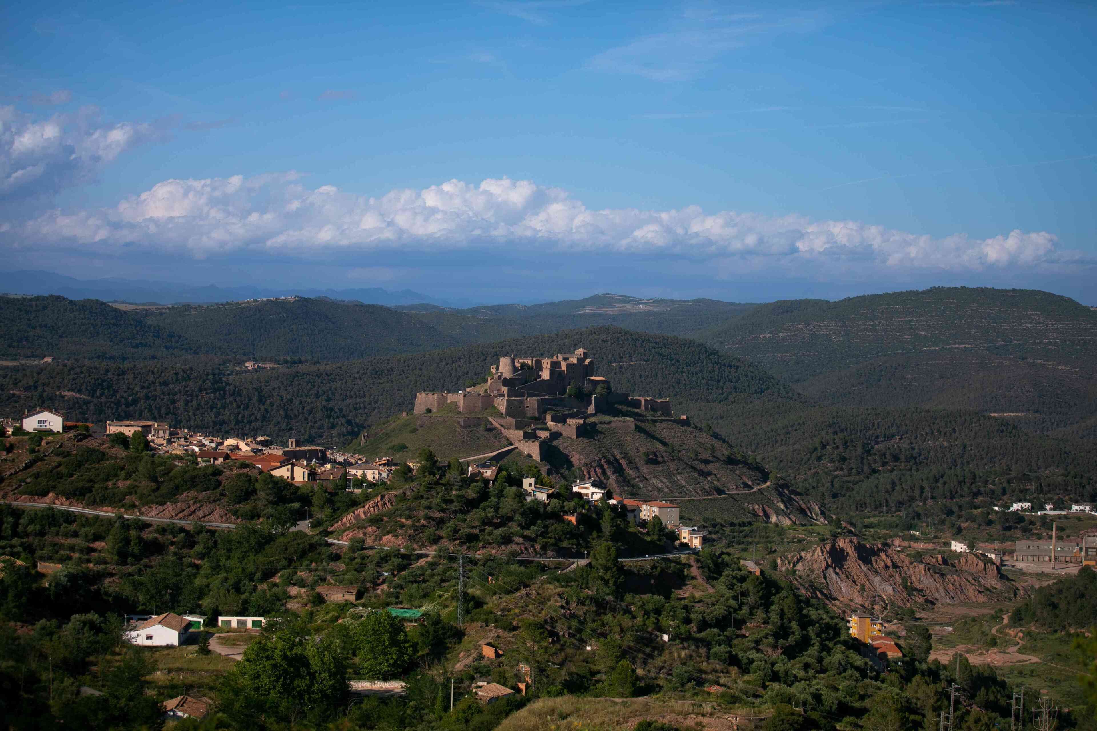 A castle on a hill with surrounding buildings and a clear sky.