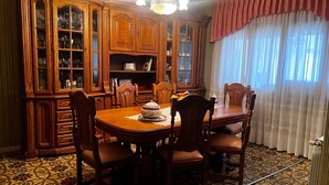 Une salle à manger avec une table en bois, des chaises, un buffet et un sol à motifs.
