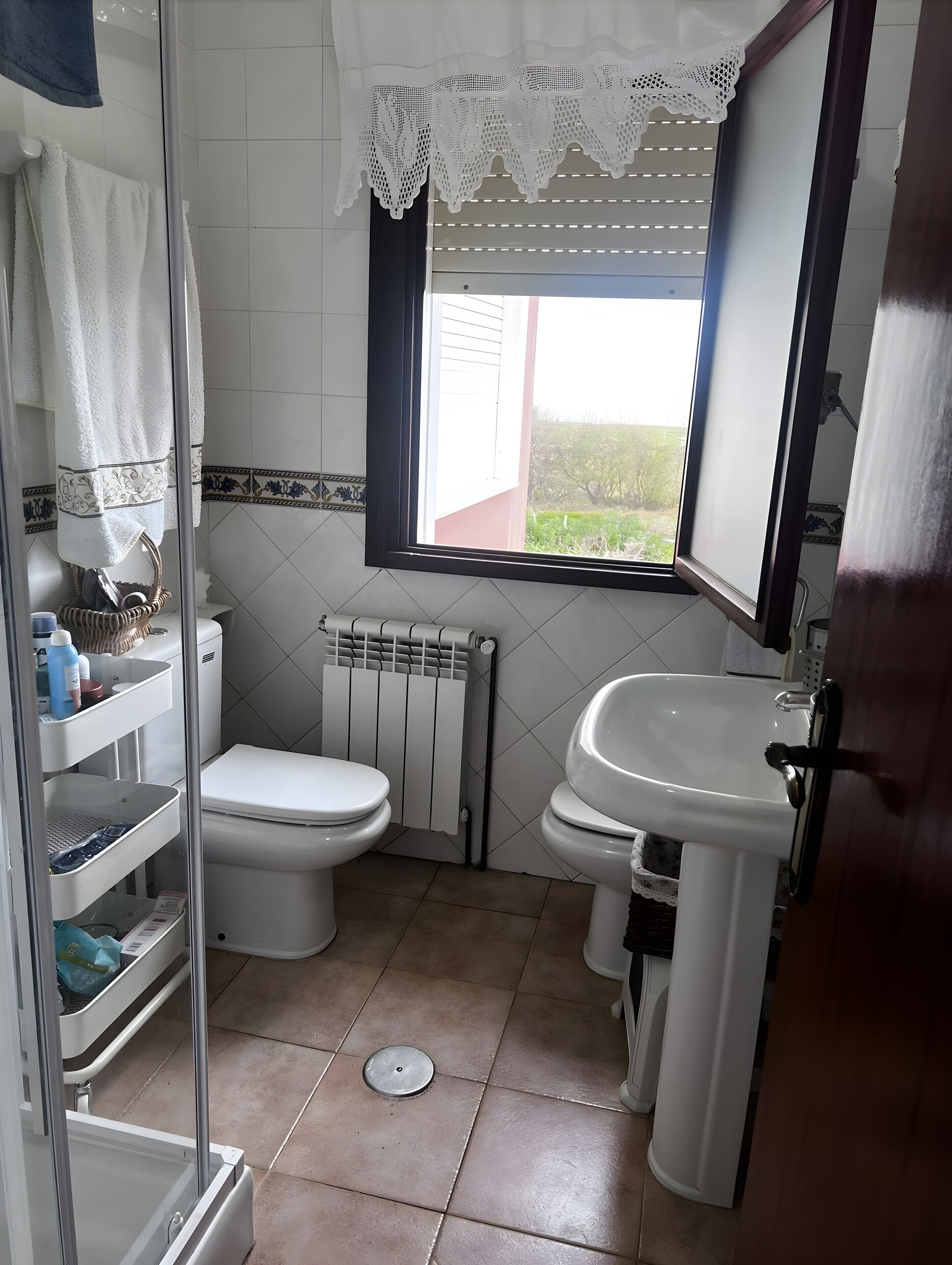 A bathroom with a toilet, sink, and window.