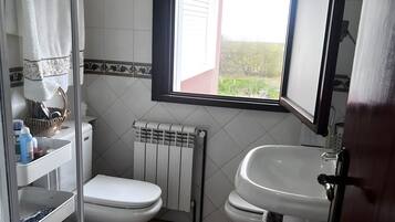 A bathroom with a toilet, sink, and window.