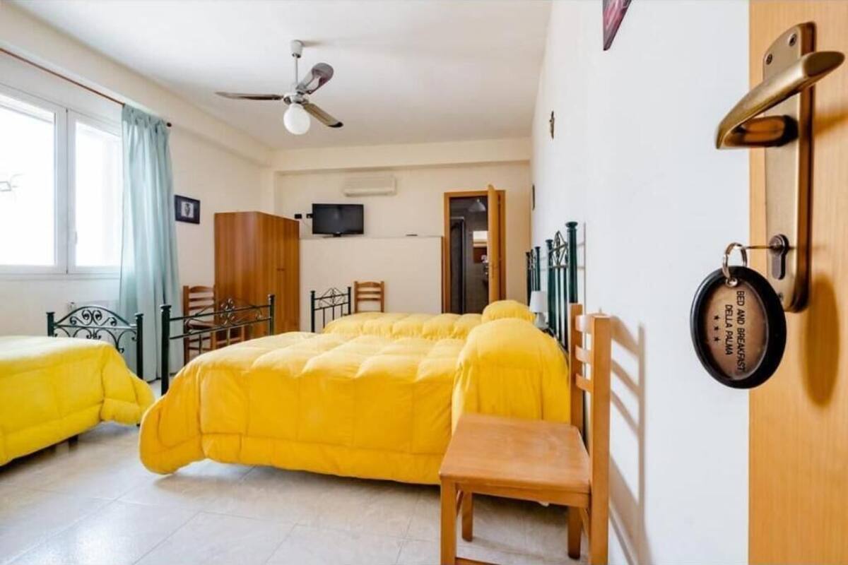 Une chambre avec deux lits, un ventilateur de plafond, une télévision et une porte fermée à clé.