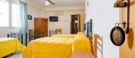 A room with two beds, a ceiling fan, a television, and a door with a key lock.