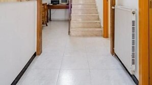A hallway with a staircase, framed pictures, and a radiator. - bed and breakfast della palma (Gela)