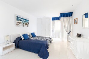 A bedroom with a bed, nightstand, dresser, and a painting on the wall. - La Manga Club Los Olivos Apartment 169 (Atamaría)