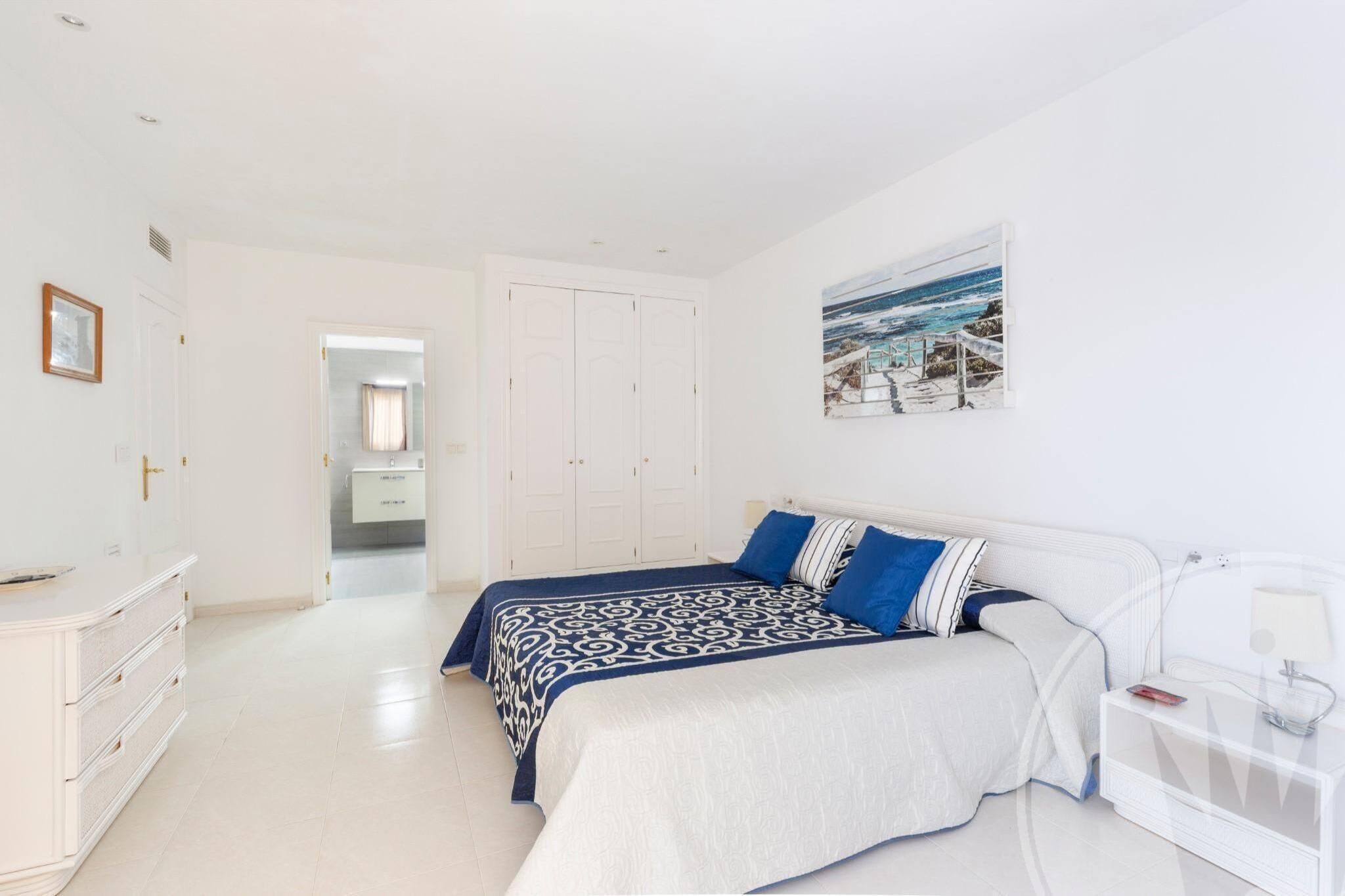 Une chambre à coucher avec un lit, une table de chevet et un tableau accroché au mur.
