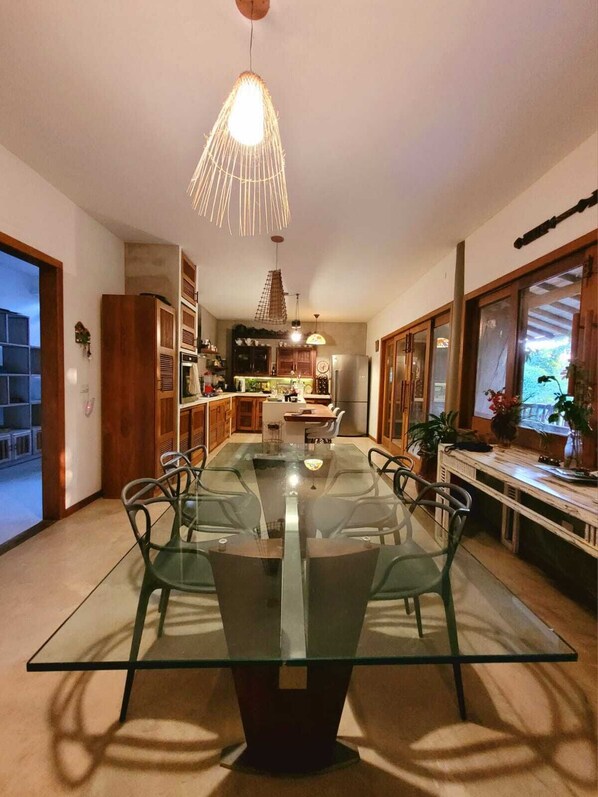 Une cuisine moderne avec une table à manger en verre, des armoires en bois et un luminaire suspendu.