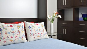 A bed with two decorative pillows, a vase with flowers, and a dark wooden dresser with drawers. - Cjour loft Apartment (Montréal)