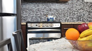 A kitchen with a stainless steel refrigerator, double oven, and a tiled backsplash. - Cjour loft Apartment (Montréal)