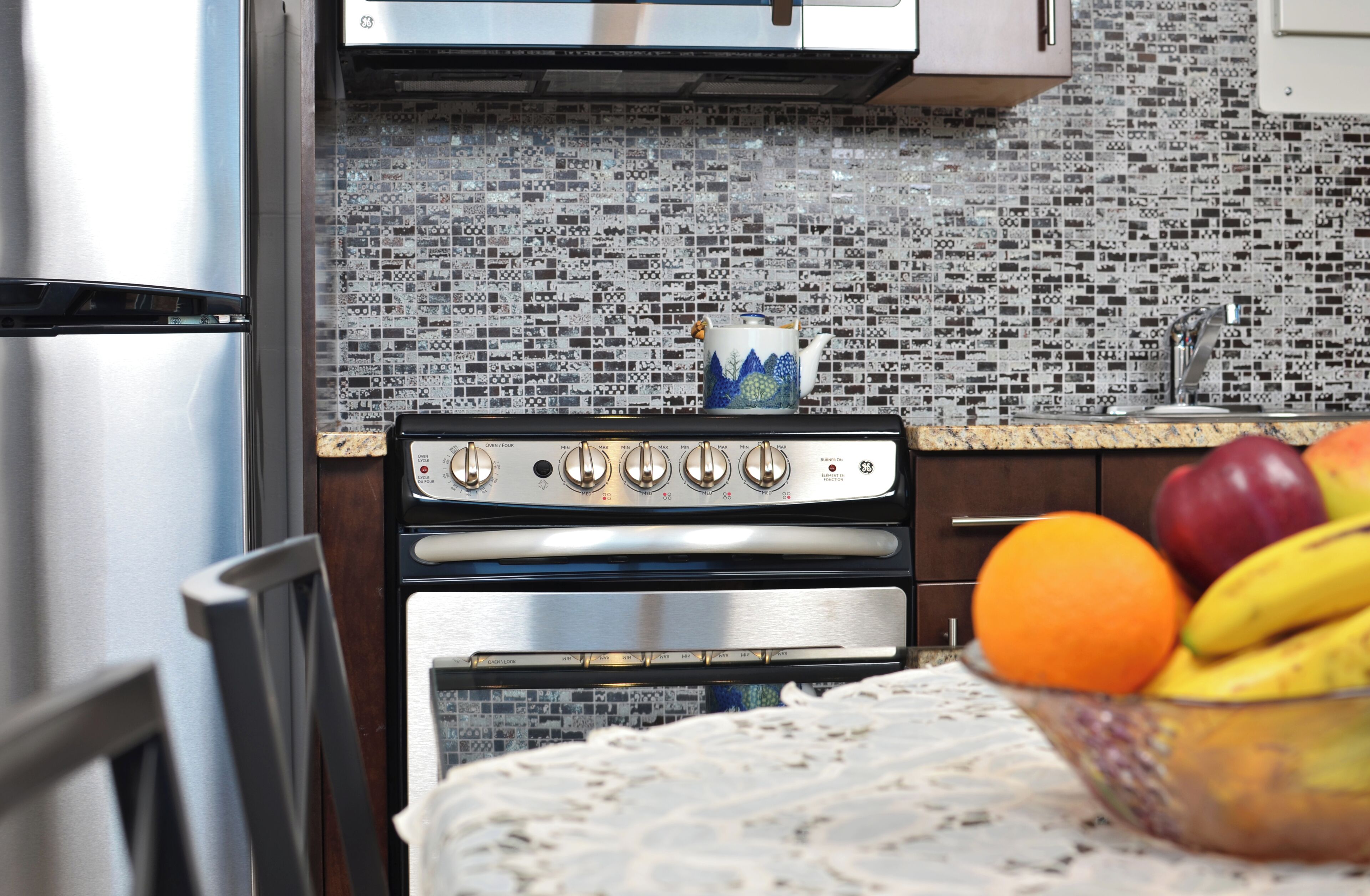 A kitchen with a stainless steel refrigerator, double oven, and a tiled backsplash.