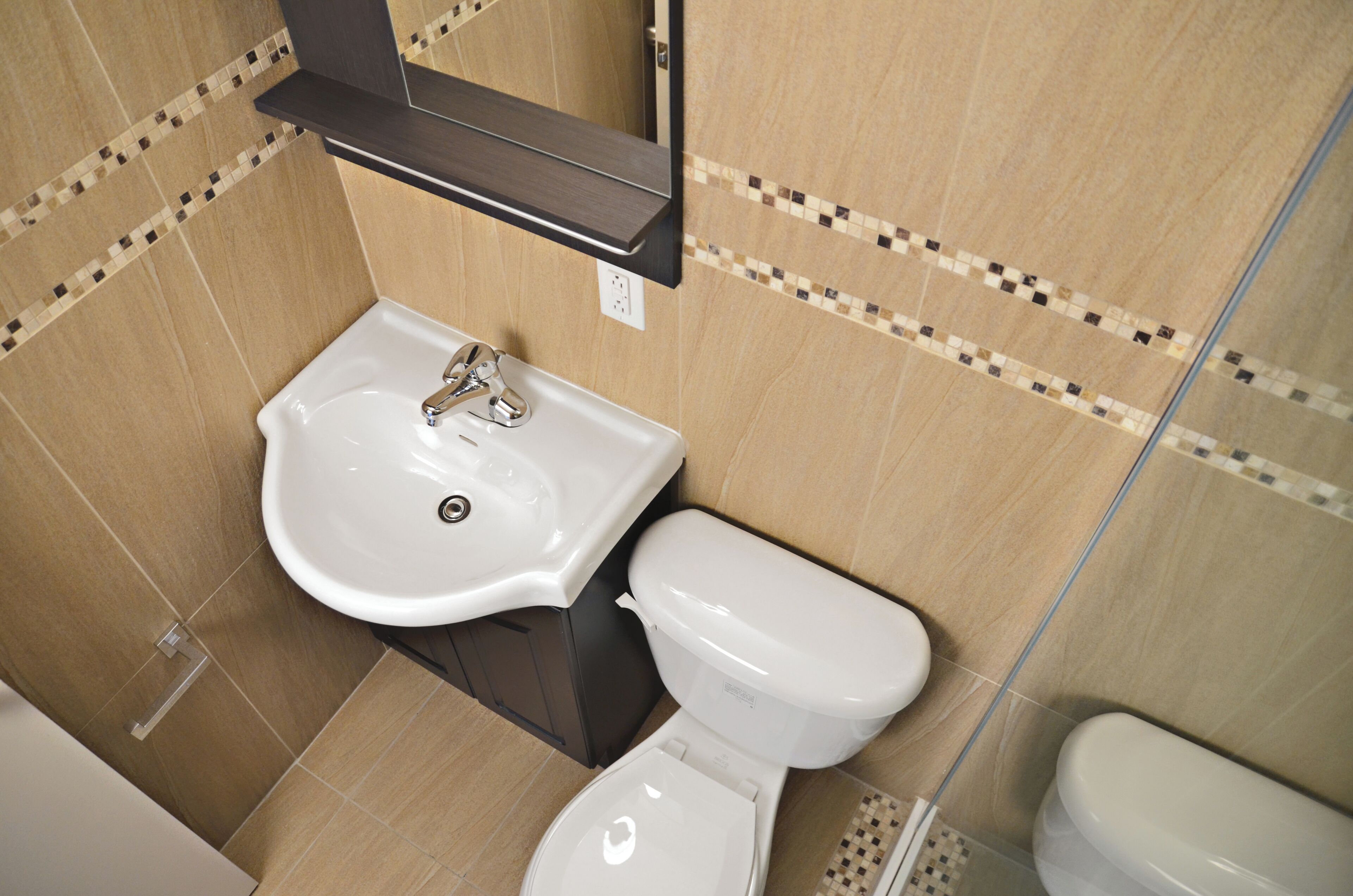 Une salle de bain avec un lavabo blanc, des toilettes et un miroir au-dessus du lavabo.