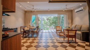 A modern kitchen with a checkered floor, dining area with chairs, a sofa, and a balcony with a view. - Staymaster Solintra 2BHK C402 (Verem)