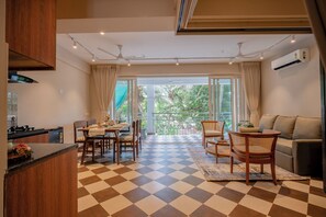 A modern kitchen with a checkered floor, dining area with chairs, a sofa, and a balcony with a view. - Staymaster Solintra 2BHK C402 (Verem)