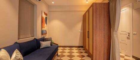 A room with a checkered floor, a blue sofa with cushions, a ceiling fan, and a door with curtains.