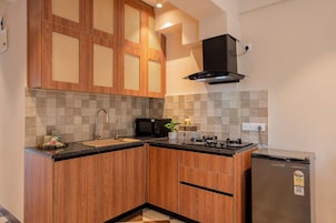 Una cocina con armarios de madera, un refrigerador de acero inoxidable, un microondas y un lavamanos.
