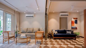 A living room with a sofa, chairs, a coffee table, and a checkered floor. - Staymaster Solintra 2BHK C402 (Verem)