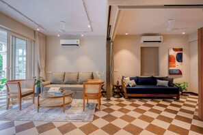 A living room with a sofa, chairs, a coffee table, and a checkered floor. - Staymaster Solintra 2BHK C402 (Verem)