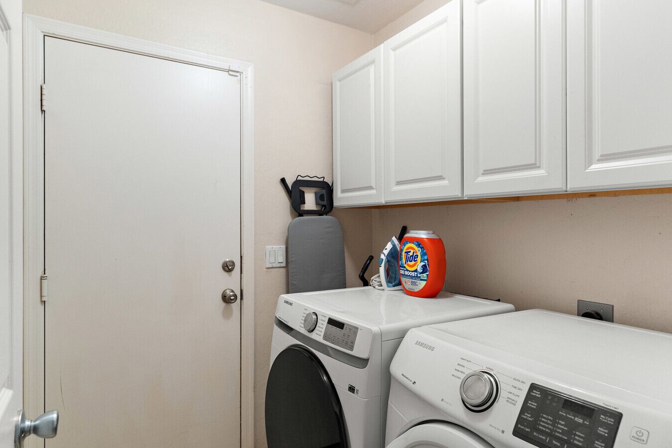 Un espace buanderie équipé d’un lave-linge, d’un sèche-linge et de lessive Tide.