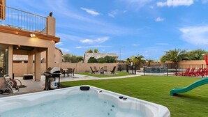 A backyard with a hot tub, outdoor furniture, a slide, and a pool.