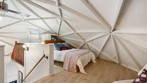 A triangular room with a bed, a wooden ladder, and a ceiling fan. - Creekside Dome with Firepit (Carroll County)