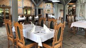 A restaurant with wooden chairs and tables, brick walls, and large windows. - Gästehaus am Elberadweg by Hotel Alte Fischerkate (Lenzerwische)