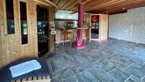 A spa area with wooden walls, a stone floor, a massage table, and a stone fireplace. - Gästehaus am Elberadweg by Hotel Alte Fischerkate (Lenzerwische)