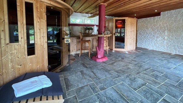 Un espace spa avec des murs en bois, un sol en pierre, une table de massage et une cheminée en pierre.