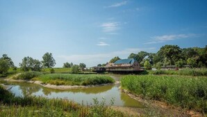 A riverside property with a house, a bridge, and a pond. - Gästehaus am Elberadweg by Hotel Alte Fischerkate (Lenzerwische)