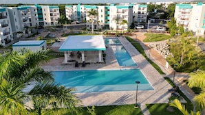 A residential complex with multiple apartment buildings, a central swimming pool, and surrounding greenery. - Luxurious Punta Cana Apartment Comfort, Convenience, and Caribbean Charm (Punta Cana)